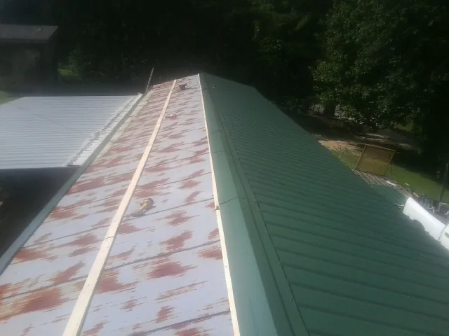 Old rusted panels beside newly installed green metal roofing — Wind Damage Roof Repair by Roofing Brothers in Forks Of Salmon
