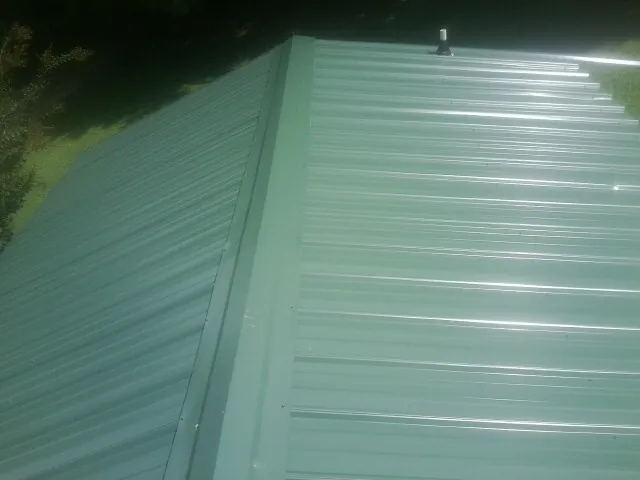 New green metal panels meeting at the ridge of a roof — Flat Roof Repair work by our crew in Forks Of Salmon