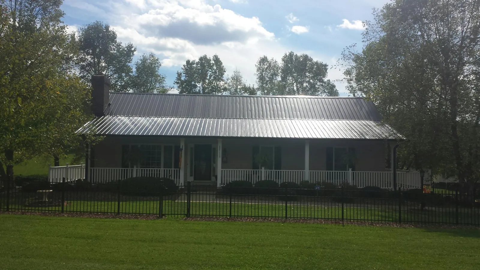 Gray metal roof on a brick ranch with a full width front porch — Gutter Guard Installation work by our crew in Forks Of Salmon
