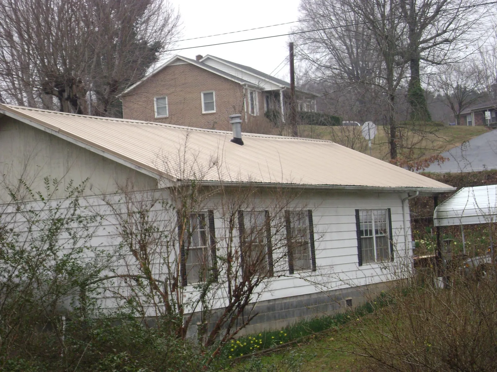 Tan metal roof on a white sided house set into a hillside — Commercial Roofing by Roofing Brothers in Forks Of Salmon