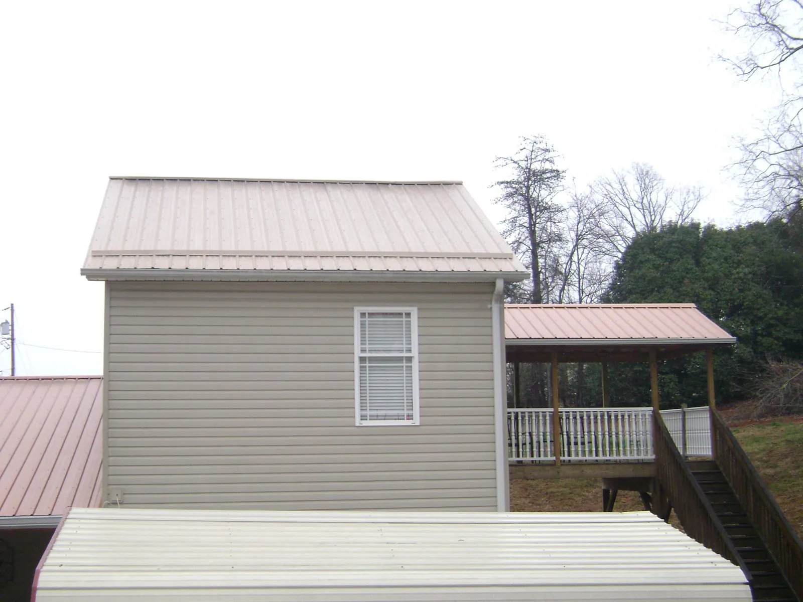 Tan metal roofs on a two story addition and attached porch, from a Roof Replacement job in Forks Of Salmon