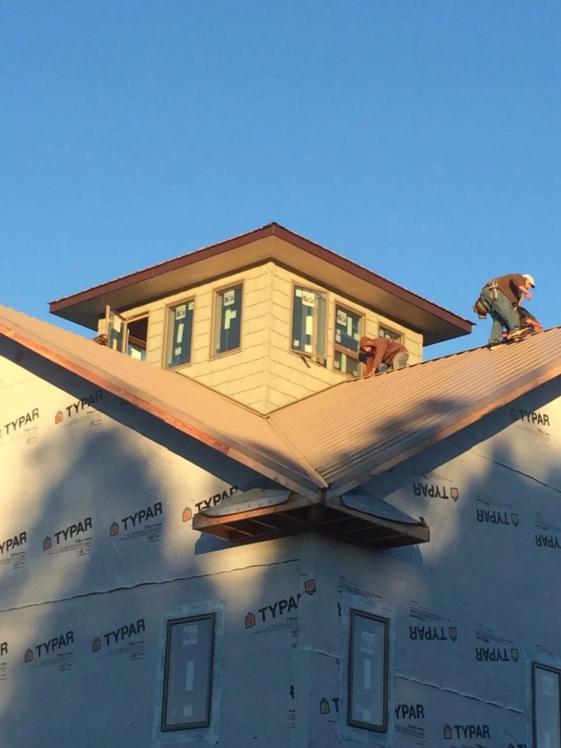 Roofers working around a rooftop cupola on a new metal roof at sunset — Roof Waterproofing in Forks Of Salmon by Roofing Brothers